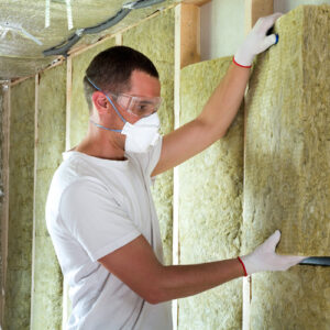 Man placing batts of insulation in wall